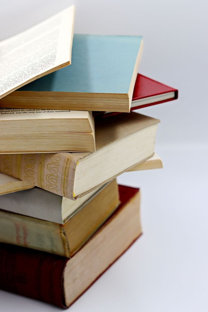 A vertical stack of various hardcover books with visible pages, ideal for literature themes.