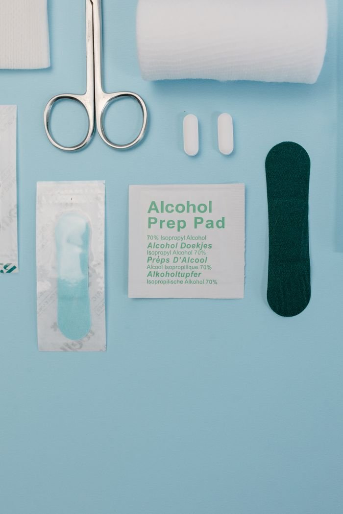 hero-about Top view of medical supplies including gauze, scissors, and alcohol prep pad on blue background.